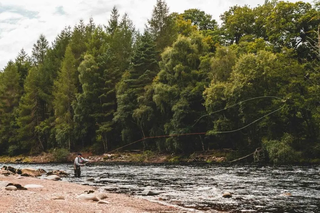 Ian Neale Spey casting in a wooded river, fly line looping out over the water