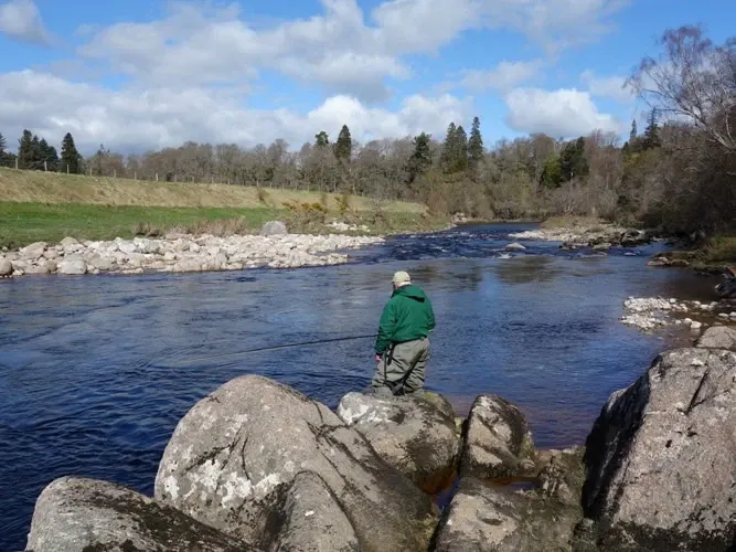 An angler casts from rocks at the Kennel pool, Glenferness Estate on the River Findhorn