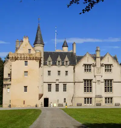 Brodie Castle turrets and crow stepped gables under a clear blue sky with a tree lined driveway