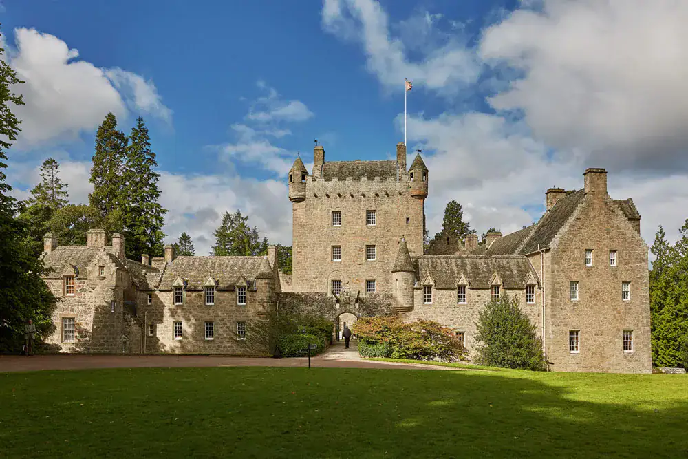Cawdor Castle turrets and crow stepped gables rise above green lawns under a blue sky