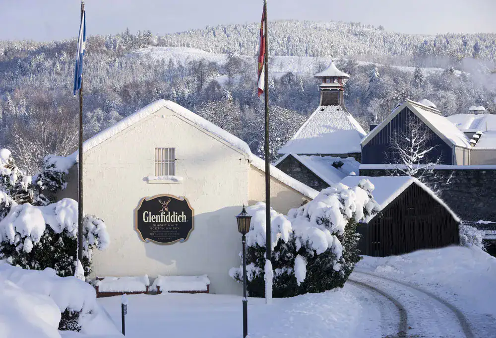 Glenfiddich distillery buildings and pagoda roof covered in deep snow under a wintry sky