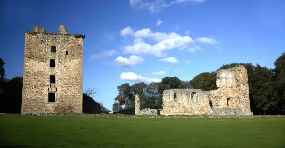 Ruins of Spynie Castle's tower and palace walls under a blue sky with scattered clouds